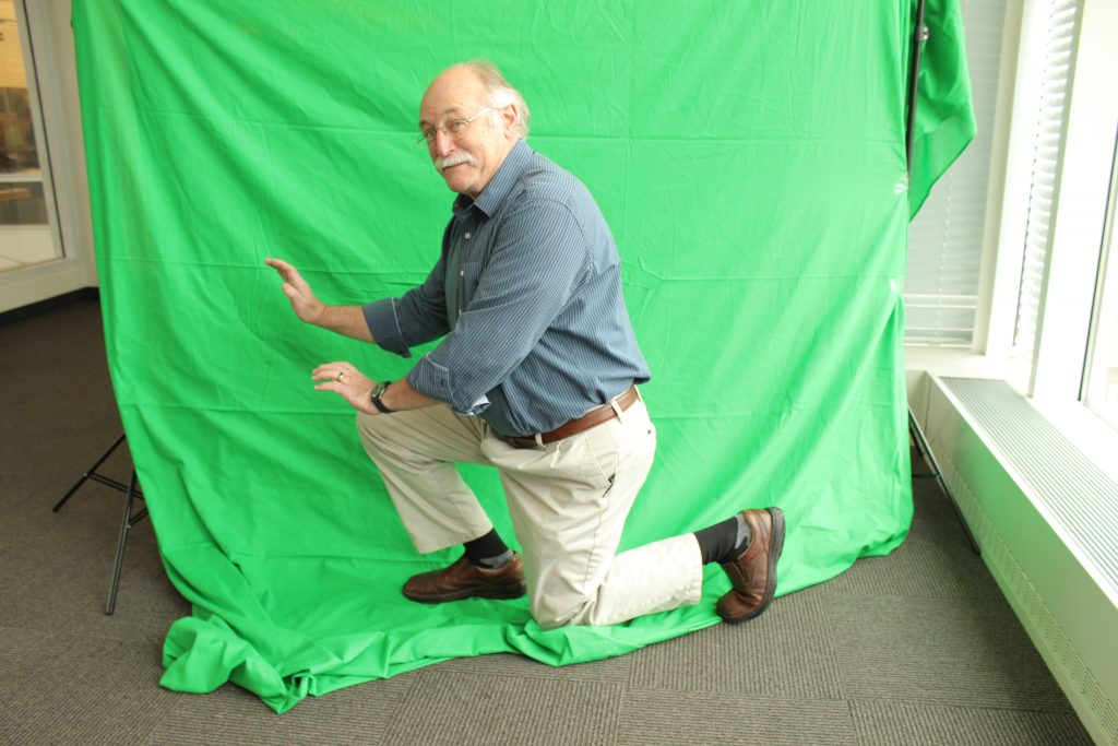 Man kneeling in front of a green screen