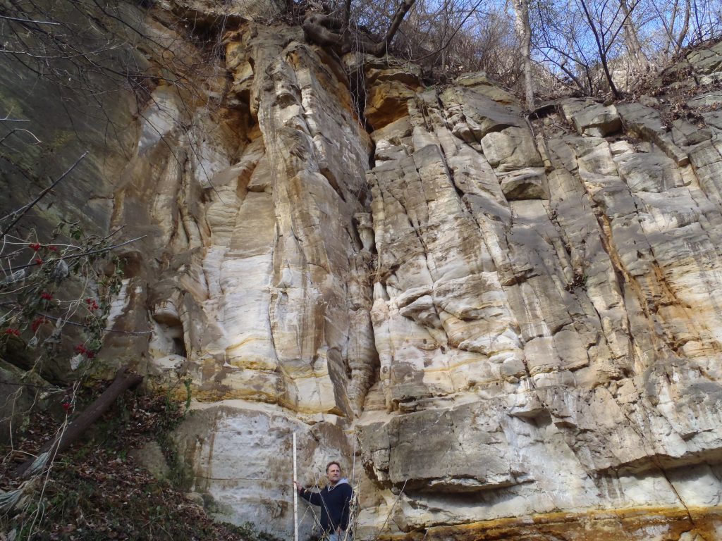 Photograph of Tony Runkel standing next to an outcrop of fractured Jordan sandstone.