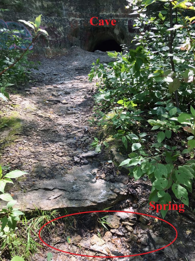 Photograph of Echo cave. The cave has a dirt path leading up to it and is carved out of rock.